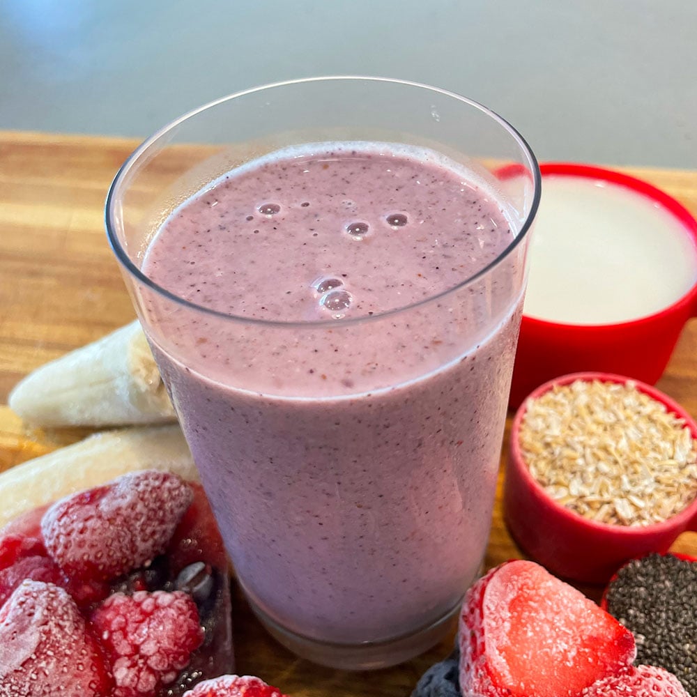 Smoothie in a glass on the counter surrounded by ingredients