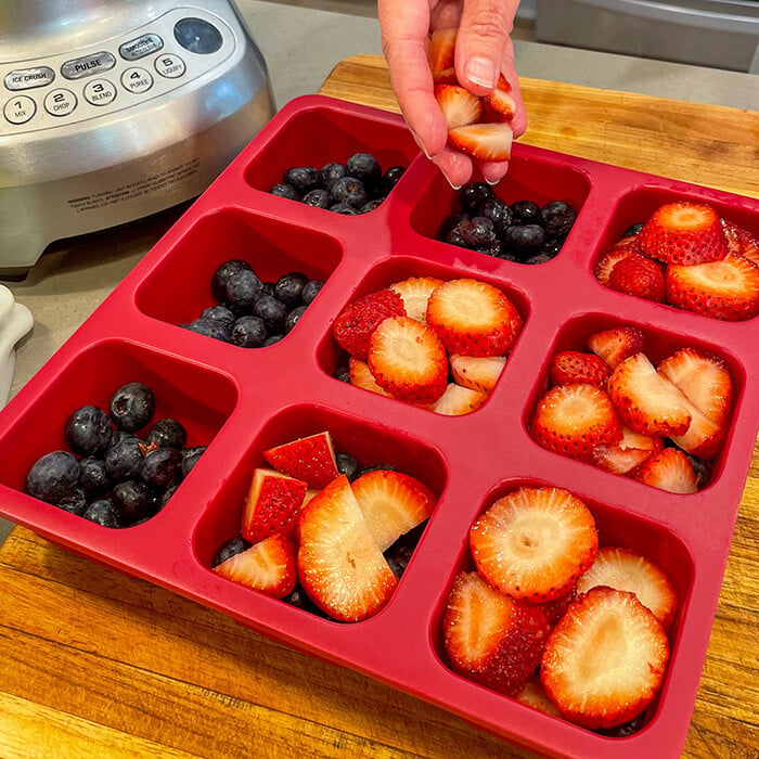 Berries being placed in a silicone freezer tray