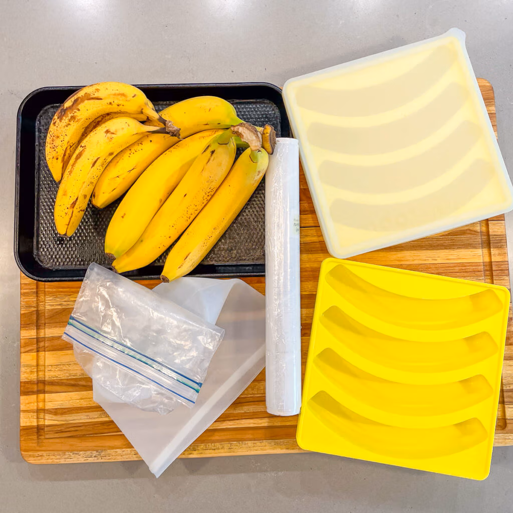 Various types of containers to freeze bananas, including Smootheeze trays, plastic bags, and a baking sheet