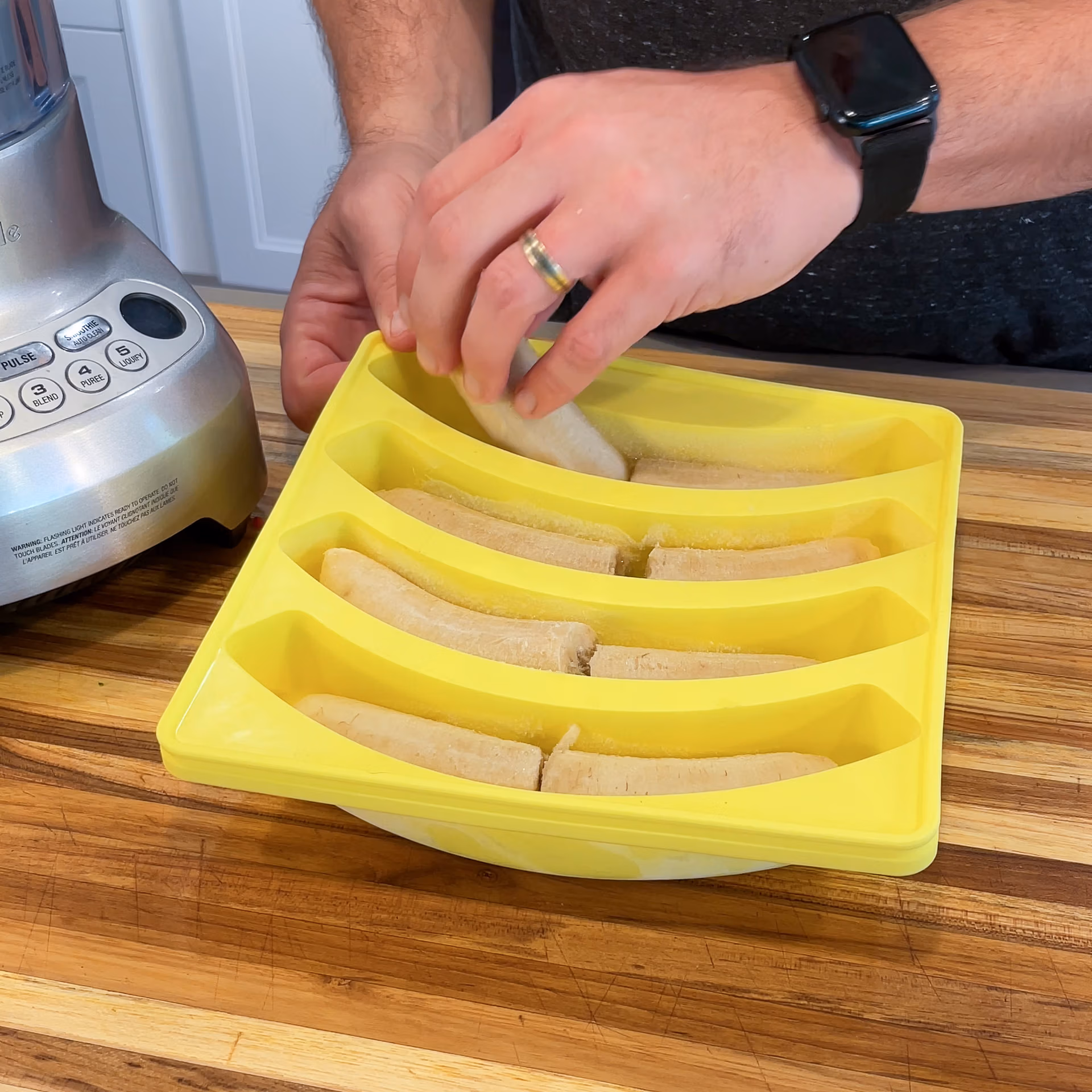Smootheeze banana shaped silicone freezer tray with a hand removing a banana