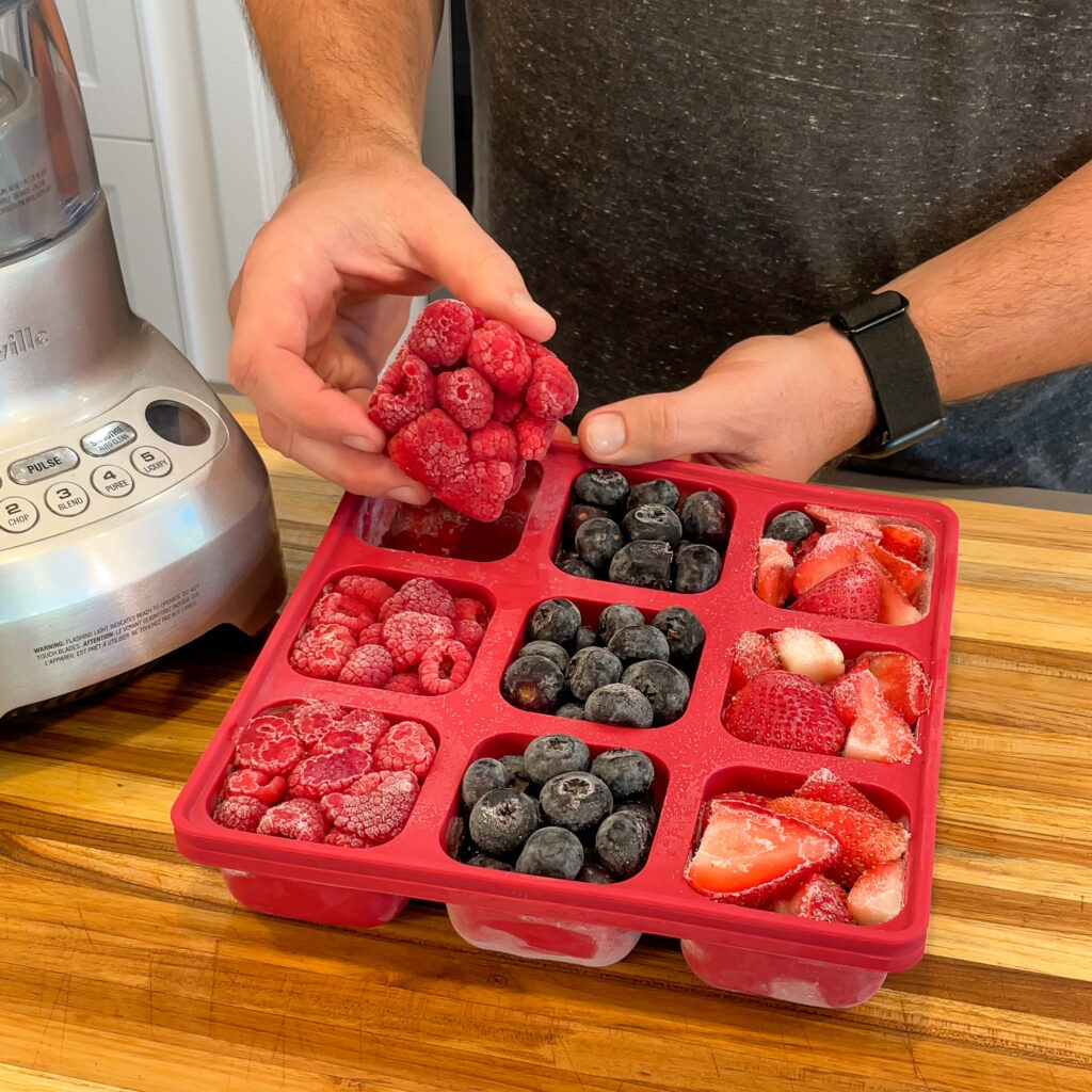 Silicone freezer tray with frozen fruits portioned into individual cubes