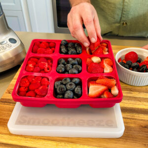 Smootheeze freezer tray being filled with raspberries, blueberries, and strawberries