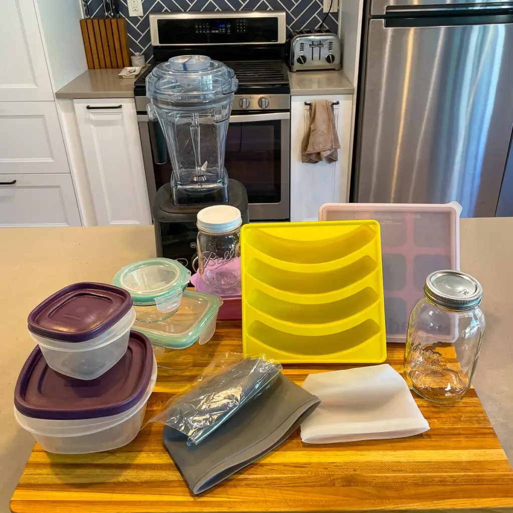 Various types of smoothie prep containers arranged on the counter, including silicone, plastic, and glass containers.