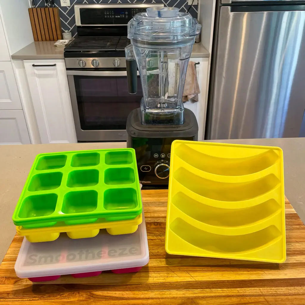 Smootheeze silicone smoothie prep containers on the counter next to a blender.