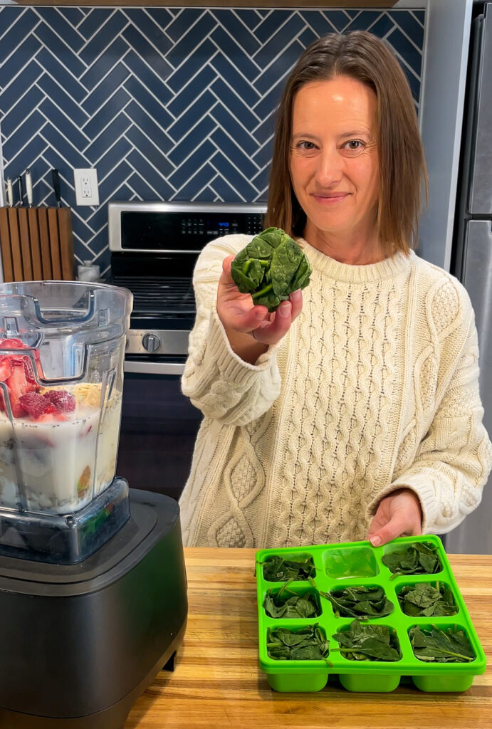 Woman placing spinach Smootheeze Cube into a blender to make a smoothie