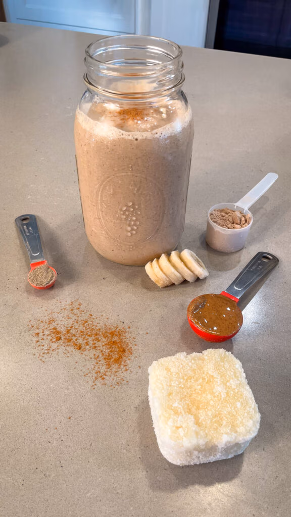 Cauliflower cinnamon roll smoothie in a glass surrounded by the base ingredients