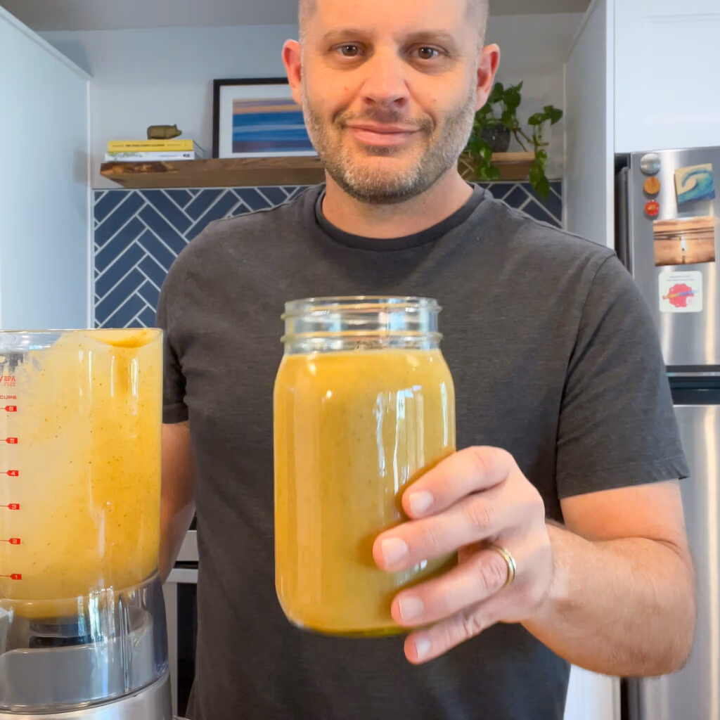 A person holding a blended smoothie up towards the camera