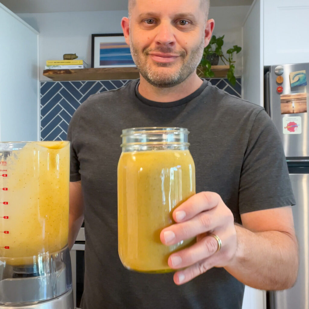 A person holding a blended smoothie up towards the camera