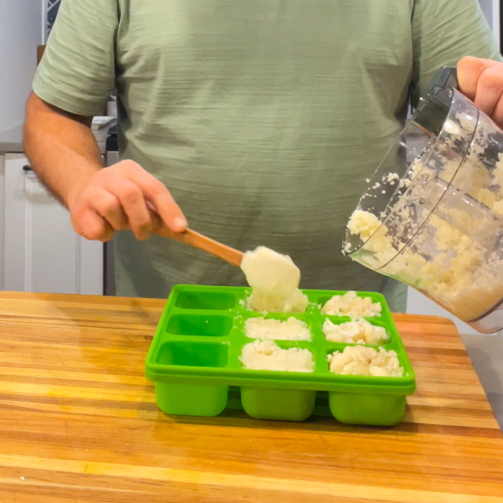 Scooping riced cauliflower into a Smootheeze freezer tray to make frozen cubes