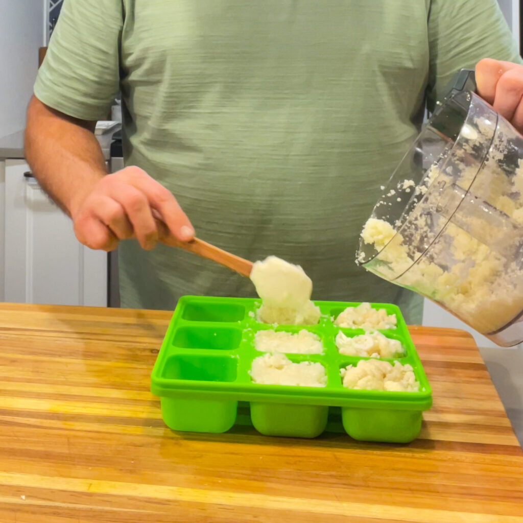 Scooping riced cauliflower into a Smootheeze freezer tray to make frozen cubes