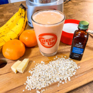 Smoothie in a glass made from oranges, carrots, oats, and ginger