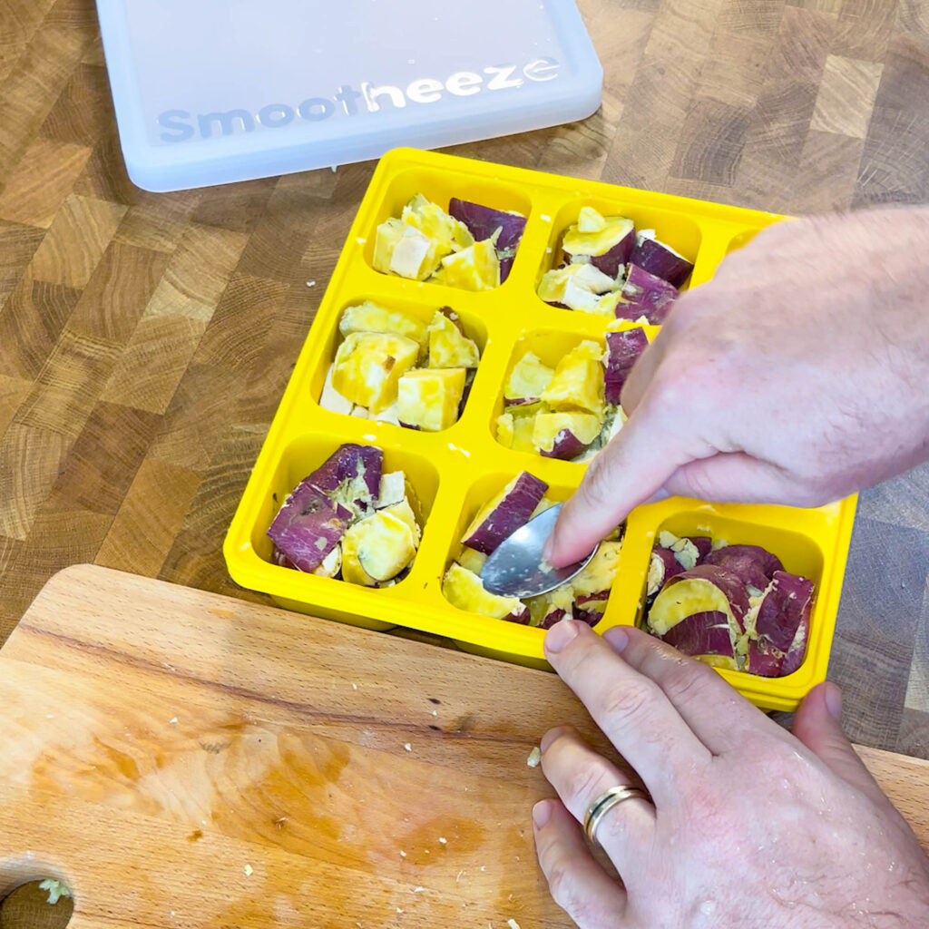 Mashing the cooked sweet potatoes in a Smootheeze freezer tray to freeze them for smoothies
