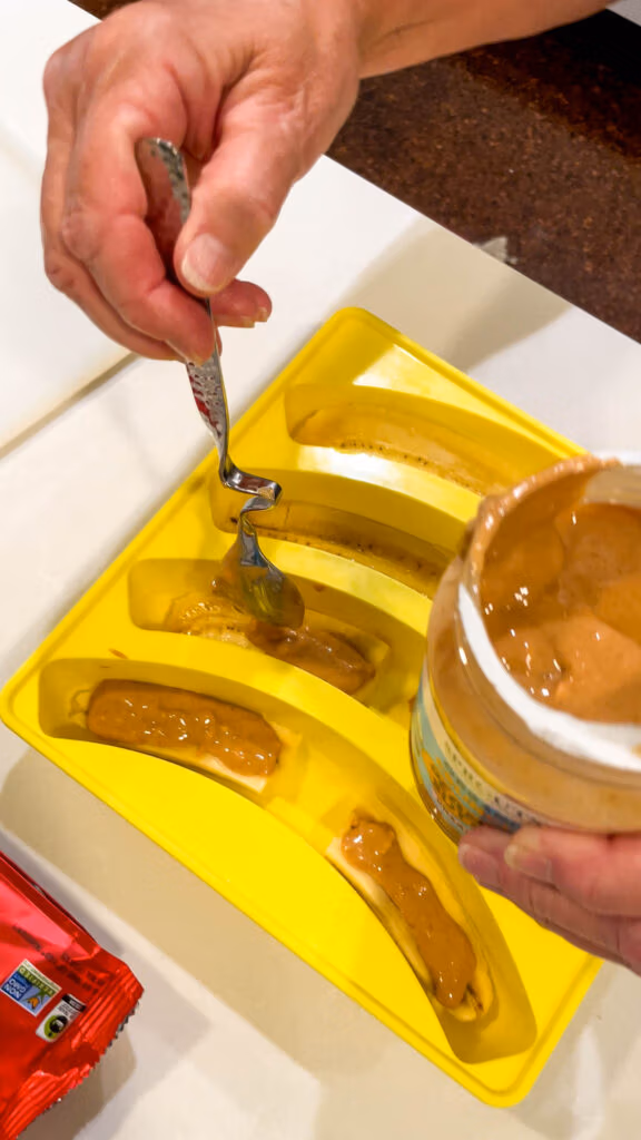 Spreading peanut butter across banana slices