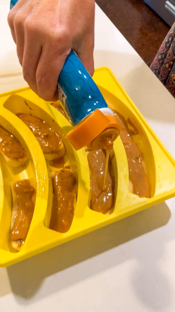 Drizzling caramel sauce over peanut butter topped bananas