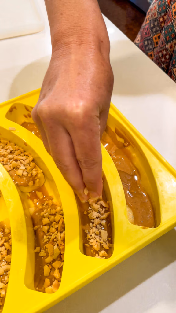 Sprinkling crushed peanuts over the caramel layer